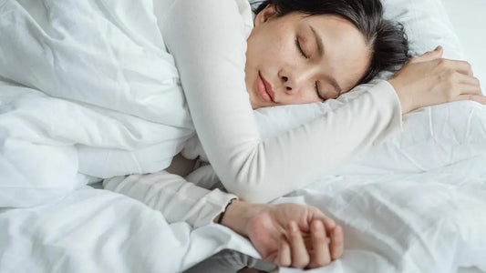 Asian woman in white pajamas sleeping with best mouth tape for sleeping, morning light on white sheets.